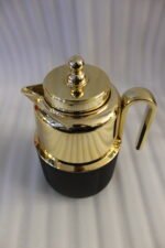 Three One More 1 liter luxury thermal vacuum flasks in black, white, and grey with polished gold tops on a marble kitchen countertop.