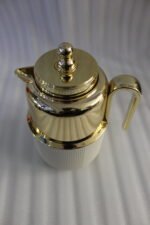 Three One More 1 liter luxury thermal vacuum flasks in black, white, and grey with polished gold tops on a marble kitchen countertop.