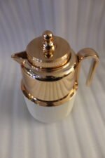 One More 1 Liter white fluted thermal flask with a polished rose gold lid, spout, and ergonomic handle on a kitchen countertop.