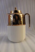 One More 1 Liter white fluted thermal flask with a polished rose gold lid, spout, and ergonomic handle on a kitchen countertop.
