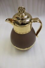 Three luxury 1-liter thermal coffee and tea vacuum flasks with ornate gold lids and accents in matte black, cream, and taupe on a granite kitchen countertop.