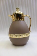 Three luxury 1-liter thermal coffee and tea vacuum flasks with ornate gold lids and accents in matte black, cream, and taupe on a granite kitchen countertop.