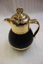 Three luxury 1-liter thermal coffee and tea vacuum flasks with ornate gold lids and accents in matte black, cream, and taupe on a granite kitchen countertop.